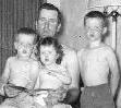 My dad holding my brother, Dick and me, with another brother standing next to us.  Click for view that includes my sister and our 50's furniture.