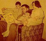 Dad holding his children and reading a book to them.