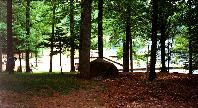 A tent in the woods near the water.