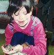 Anna holding two toads, one on her arm, one on her hand.