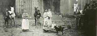 Anna, standing in front of their barn with various people.  Click for much better view.